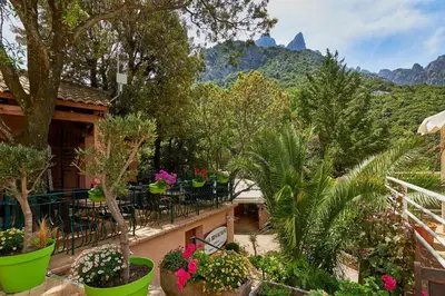 a balcony with tables and plants and mountains in the background at Camping Les Oliviers in Porto Ota