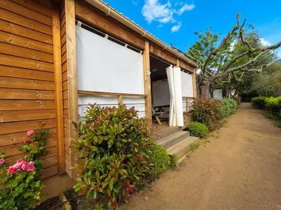 a wooden building with a porch and some flowers at Camping Les Oliviers in Porto Ota