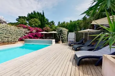 a pool with chairs and umbrellas on a wooden deck at Villas CALA CORSA - 3 chambres piscine partagée chauffée - CALA ROSSA Porto-Vecchio - Villas entièrement Climatisées - Internet gratuit in Porto-Vecchio