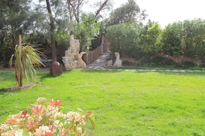 a garden with a statue in the grass at Villas CALA CORSA - 3 chambres piscine partagée chauffée - CALA ROSSA Porto-Vecchio - Villas entièrement Climatisées - Internet gratuit in Porto-Vecchio