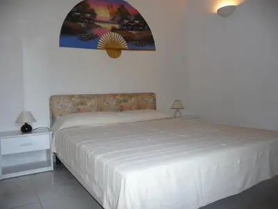 a bedroom with a bed and a painting on the wall at Résidence Playa Del'Oro in Favone