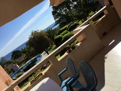 a chair sitting on a balcony looking out at the ocean at Résidence Playa Del'Oro in Favone