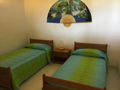 a bedroom with two beds and a painting on the wall at Résidence Playa Del'Oro in Favone
