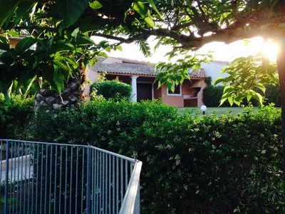 a fence in front of a house with trees and bushes at Résidence Playa Del'Oro in Favone