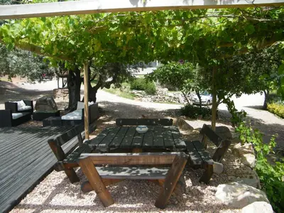 a picnic table and a bench under a pergola at Les Jardins de Mathieu in Porto-Vecchio