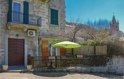a green umbrella sitting on a fence in front of a building at 1 Bedroom Cozy Apartment In Zonza in Zonza