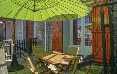 a wooden table and chairs under a green umbrella at 1 Bedroom Cozy Apartment In Zonza in Zonza