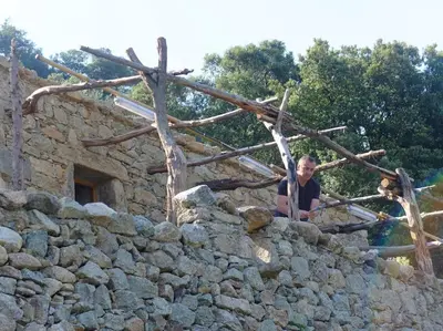 a man sitting on top of a stone wall at Les Bergeries 