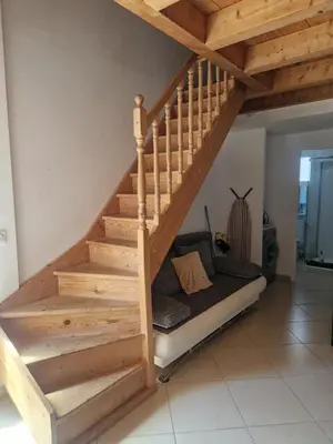 a wooden staircase in a room with a couch under it at Les Chênes Verts in Corte