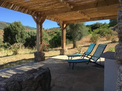 two chairs and a table under a wooden pergola at Casa Lysandra in Serra-di-Ferro