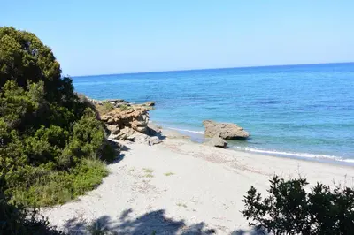 a sandy beach with rocks and the ocean at La Tour in Linguizzetta