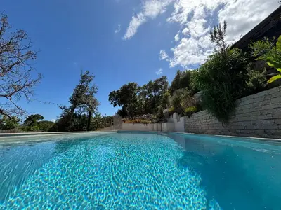 a swimming pool with blue water in front of a building at Villa Santa in Porto-Vecchio