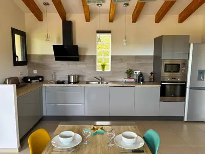 a kitchen with white cabinets and a table with chairs at Villa Santa in Porto-Vecchio