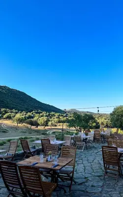 a group of tables and chairs with mountains in the background at L'Aghjalle in Santa-Reparata-di-Balagna