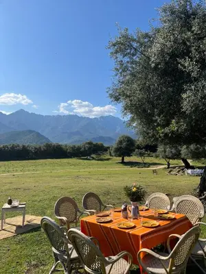 an orange table and chairs with mountains in the background at L'Aghjalle in Santa-Reparata-di-Balagna