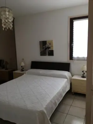 a bedroom with a white bed and a window at Rez de Villa Vue Mer Panoramique in Furiani