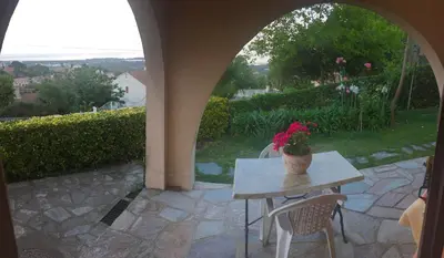 a table with a vase of flowers on a patio at Rez de Villa Vue Mer Panoramique in Furiani