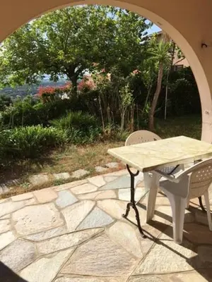 a table and chairs on a stone patio with an archway at Rez de Villa Vue Mer Panoramique in Furiani