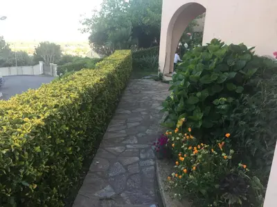 a garden with flowers and a stone walkway at Rez de Villa Vue Mer Panoramique in Furiani