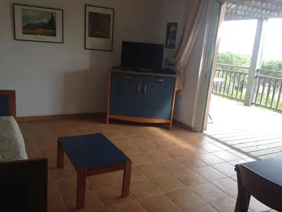 a living room with a tv on a dresser with a sliding door at Villa Les Hameaux Di Santa Giulia in Porto-Vecchio