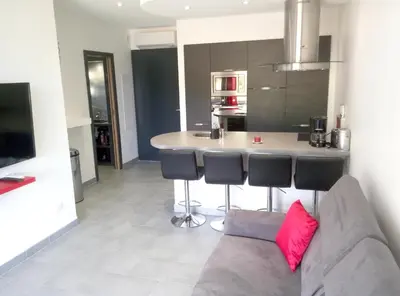 a living room with a couch and a kitchen at Appartement charmant à Olmeta di Tuda avec piscine partagée in Olmeta-di-Tuda