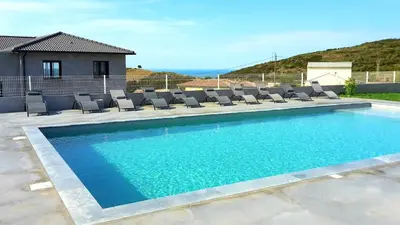 a swimming pool with lounge chairs and a house at Appartement charmant à Olmeta di Tuda avec piscine partagée in Olmeta-di-Tuda