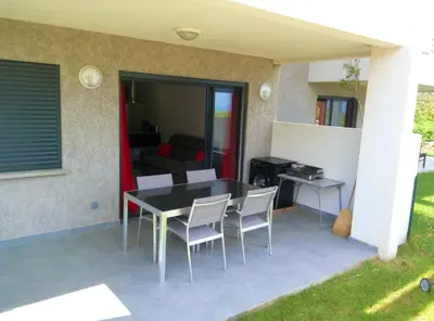 a patio with a table and chairs and a couch at Appartement charmant à Olmeta di Tuda avec piscine partagée in Olmeta-di-Tuda