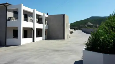 a large white building with a hill in the background at Appartement charmant à Olmeta di Tuda avec piscine partagée in Olmeta-di-Tuda