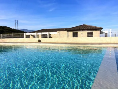 a pool of blue water in front of a building at Appartement charmant à Olmeta di Tuda avec piscine partagée in Olmeta-di-Tuda