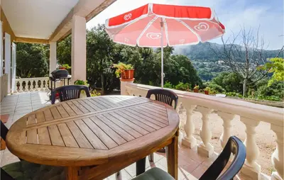 a wooden table with chairs and an umbrella on a balcony at Villa Nicolas in Coti-Chiavari