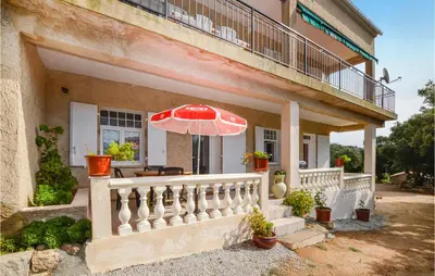 a house with a balcony with an umbrella at Villa Nicolas in Coti-Chiavari