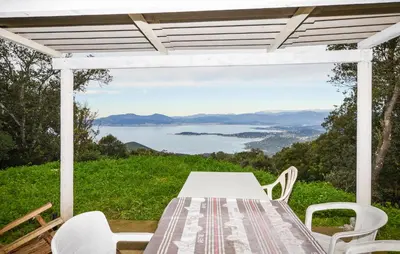 a table and chairs on a patio with a view of the water at Villa Nicolas in Coti-Chiavari