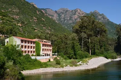 a building on the side of a river next to a mountain at Le Marina in Porto Ota