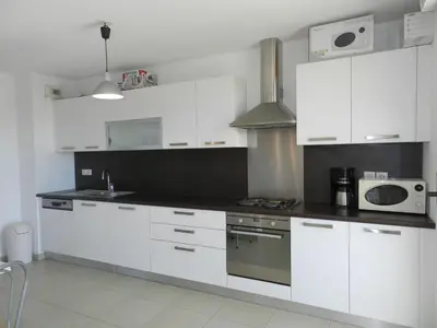 a kitchen with white cabinets and a stove top oven at Apartment Lup - Les terrasses d'Alistro by Interhome in San-Giuliano