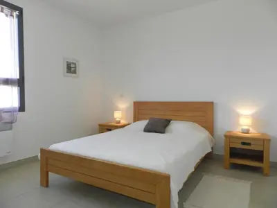 a bedroom with a bed with two night stands and two lamps at Apartment Lup - Les terrasses d'Alistro by Interhome in San-Giuliano