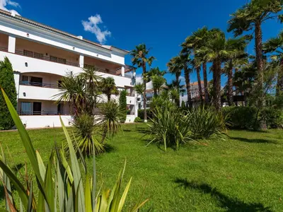 a large white building with palm trees and grass at Apartment Casa Vecchi by Interhome in Moriani Plage