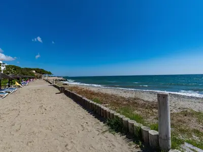 a sandy beach with a fence and the ocean at Apartment Casa Vecchi by Interhome in Moriani Plage