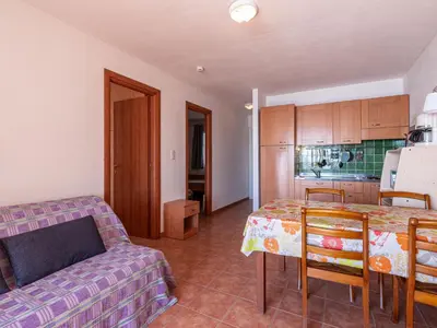 a kitchen and a living room with a table and a couch at Apartment Casa Vecchi by Interhome in Moriani Plage