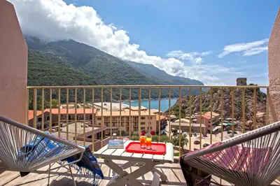 a balcony with a table and chairs and a view of a mountain at Hotel Kalliste in Porto Ota