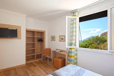 a bedroom with a window and a desk and a bed at Hotel Kalliste in Porto Ota