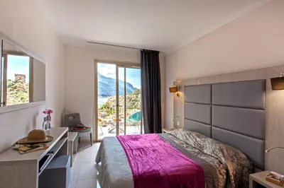 a bedroom with a bed and a desk and a window at Hotel Kalliste in Porto Ota