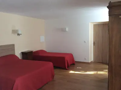 a hotel room with two beds with red sheets at Hotel Restaurant de la Poste in Aullène