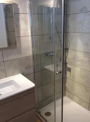 a shower with a glass door next to a sink at Hotel Restaurant de la Poste in Aullène