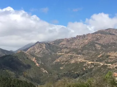 a view of a mountain range with clouds in the sky at Hotel Restaurant de la Poste in Aullène