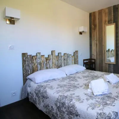 a bedroom with a large bed with a wooden headboard at Hotel Restaurant de la Poste in Aullène