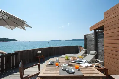 a wooden table on a deck next to the water at Domaine De Caranella in Porto-Vecchio