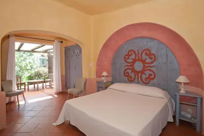a bedroom with a large bed and a patio at Domaine De Caranella in Porto-Vecchio