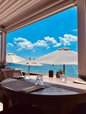 a table with two white umbrellas and the ocean at Domaine De Caranella in Porto-Vecchio