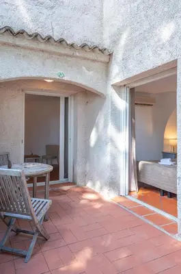 a patio with a bench and a table and a bed at Domaine De Caranella in Porto-Vecchio