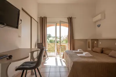 a hotel room with a bed and a desk and a television at Domaine De Caranella in Porto-Vecchio